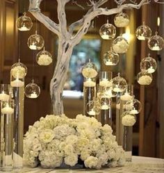 a centerpiece with flowers and candles on a table in front of a mirror wall