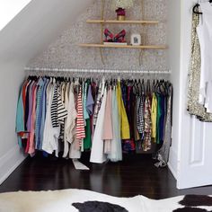 an image of a closet with clothes hanging on the rack and other items in it