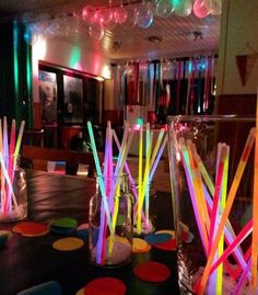 an instagram page with neon colored straws in vases on the table and balloons hanging from the ceiling