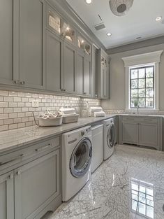 a large kitchen with marble floors and gray cabinets, along with a washer and dryer