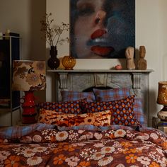 a bed with an orange and blue bedspread in front of a painting on the wall