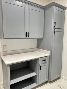 an empty kitchen with gray cabinets and marble counter tops in the center, along with white tile flooring