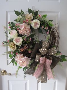 a wreath on the front door decorated with pink and white flowers