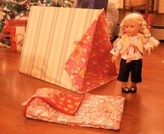 a doll is standing next to a tent on the floor in front of a christmas tree