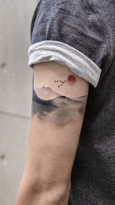 a man's arm with a mountain and stars tattoo on the left side of his arm