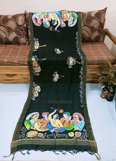 a black blanket with cartoon characters on it sitting next to a wooden bench and pillows