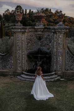 a woman standing in front of a stone fountain