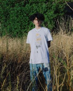 a young man standing in the middle of tall grass