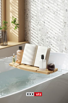 an open book sitting on top of a wooden shelf next to a bathtub filled with water