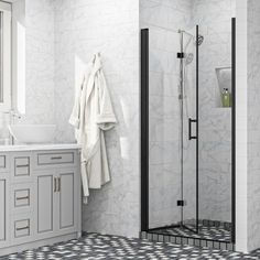 a white bathroom with black and white tile flooring on the walls, shower stall, sink and mirror