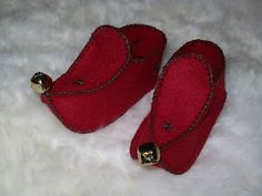 pair of red slippers on white fur with gold bells in the middle and bottom