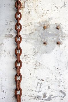 a rusty chain hanging from the side of a building