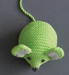 a green knitted animal head hanging on a gray wall next to it's ear