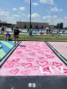 a girl standing in front of a chalk drawing on the ground with hearts drawn on it