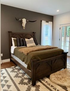 a bedroom with a bed, rug and cow skull head on the wall above it