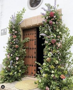 an open door surrounded by flowers and greenery