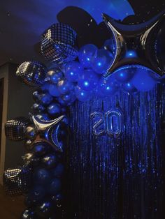 balloons and streamers in the shape of numbers are hanging from a ceiling with blue lights