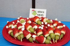 a red plate topped with fruit covered in marshmallows and apples next to a sign