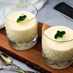 two glasses filled with pudding sitting on top of a wooden tray