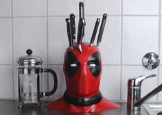 a red deadpool knife holder with knives sticking out of it's centerpiece