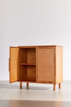 a wooden cabinet with doors and drawers on one side, in front of a white wall