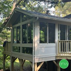 a small house in the woods with a porch and screened off area on one side