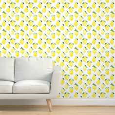 a white couch sitting in front of a wall with yellow lemons on it's side