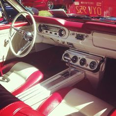 the interior of a classic car with red and white leather seats, steering wheel and dash board