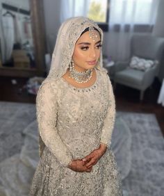 a woman in a white dress and headpiece is posing for the camera with her hands on her hips