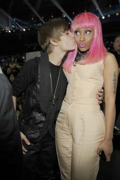 two people are kissing each other in front of an audience at a fashion show with pink hair