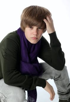 a young man wearing a purple scarf and green sweater