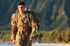 a man in camouflage walking on the beach