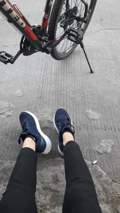 the legs and feet of a person standing next to a bicycle