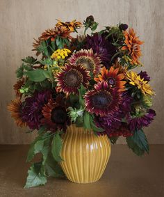 a yellow vase filled with lots of colorful flowers