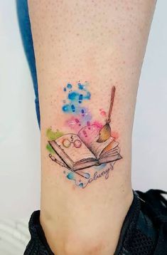 a woman's leg with a book and pencil tattoo on her left side calf