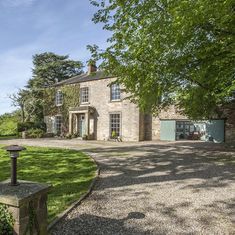 a large stone house sitting on top of a lush green field