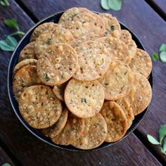 a bowl filled with crackers sitting on top of a wooden table next to leaves