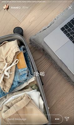 an open suitcase filled with clothes next to a laptop