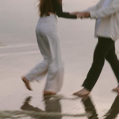 two people walking on the beach holding hands