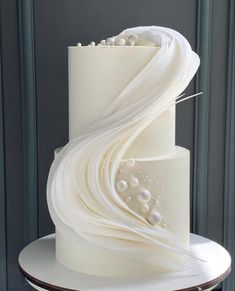 a three tiered cake with white icing and pearls