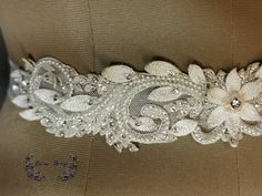 "This delicate bridal belt is made of pearls, silk threads, crystals and beads on tulle base with a organza ribbon closure. This is great for a beach, outdoor, tropical theme wedding gown Dimensions: Length - 12 inches Width at centre - 1 3/4 inch Width at edge - 1/2 inch Customisation in length and color available with additional charges. PLEASE CONTACT US BEFORE PURCHASE. Base fabric: Polyamide tulle. Base Color: ivory white. Beading/embroidery color: off white, ivory, light peach and silver F