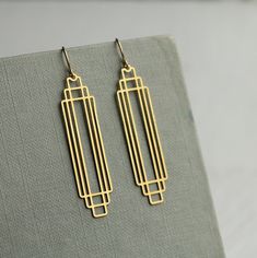 These great earrings are made with solid brass and feature a graduated art deco design.  They remind us of classic Deco architecture, like the Chrysler building!   The earrings measure 45mm (just under two inches) in length and have gold plated ear wires.   They have been designed and made in our Edinburgh studio.   This piece of handmade jewellery comes packaged in a nice recycled gift box with a handmade tag, all ready to give or keep. We also have these earrings in silver, as well as  many other Art Deco designs!  🖤 FASTER SHIPPING 🖤 Need this fast? We offer a Faster Shipping option here: https://www.etsy.com/uk/listing/100107311/faster-shipping-priority-post-upgrade 🖤 GIFT MESSAGE & WRAP SERVICE! 🖤 https://www.etsy.com/uk/listing/750160511/gift-wrap-wrapping-personalised-card?ref=l Cement Jewelry, Art Deco Jewellery Design, Gold Art Deco Earrings, Art Deco Jewellery, Silk Purse, Minimalist Earrings Gold, Deco Architecture, Deco Earrings, Chrysler Building