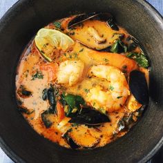 a bowl filled with shrimp and mussels next to a slice of lemon wedge