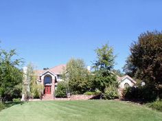 a large house in the middle of some trees and grass with a red front door