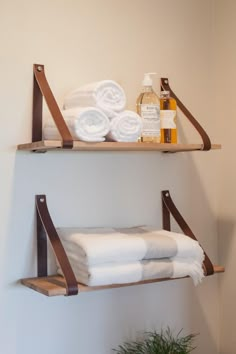 two wooden shelves with towels and soaps on them next to a potted plant