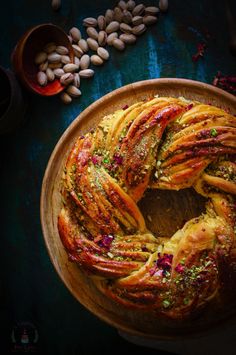 a bundt cake on a wooden platter surrounded by nuts