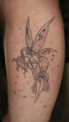 a fairy tattoo on the leg of a woman's thigh, with a flower in her hair