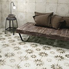 a wooden bench sitting next to a lamp on top of a table in front of a white tiled wall