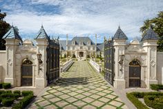 the entrance to a large mansion with an intricate gate and walkway leading into it's front yard