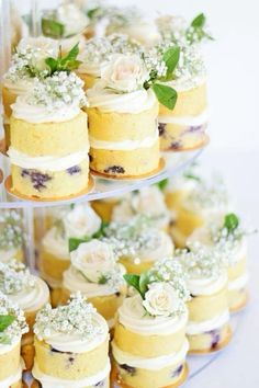 there are many small cakes on the three tiered trays that have flowers on them